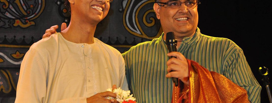 Two men standing next to each other holding microphones.